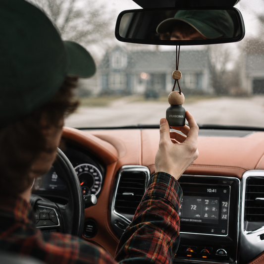 Person in a car holding a car air freshener with a brand logo.