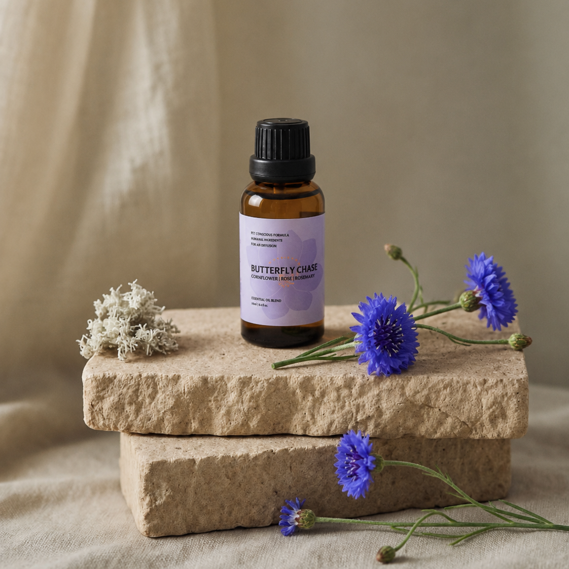 Small bottle of Butterfly Chase Furoma essential oils on a stone surface with blue flowers and white flowers on a beige background