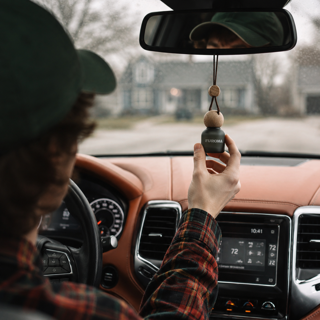Person in a car holding a car air freshener with a brand logo.